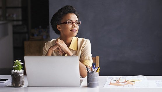 A woman at her laptop looking off to the side