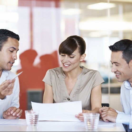 Three people discussing over some notes at a table