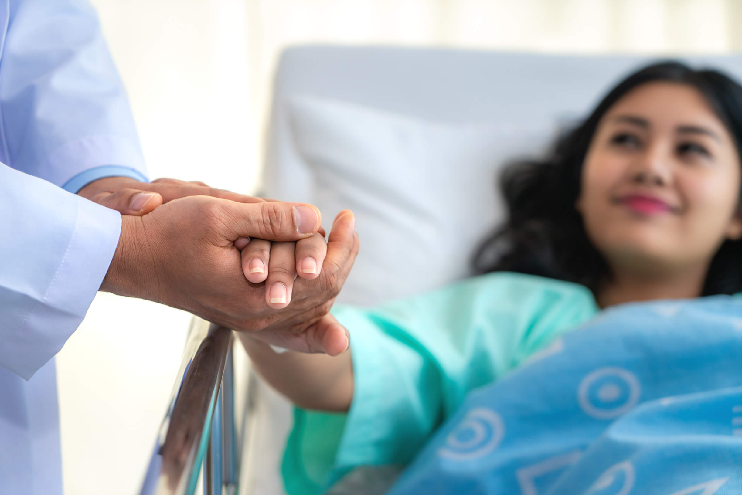 A woman clasping the hand of her doctor